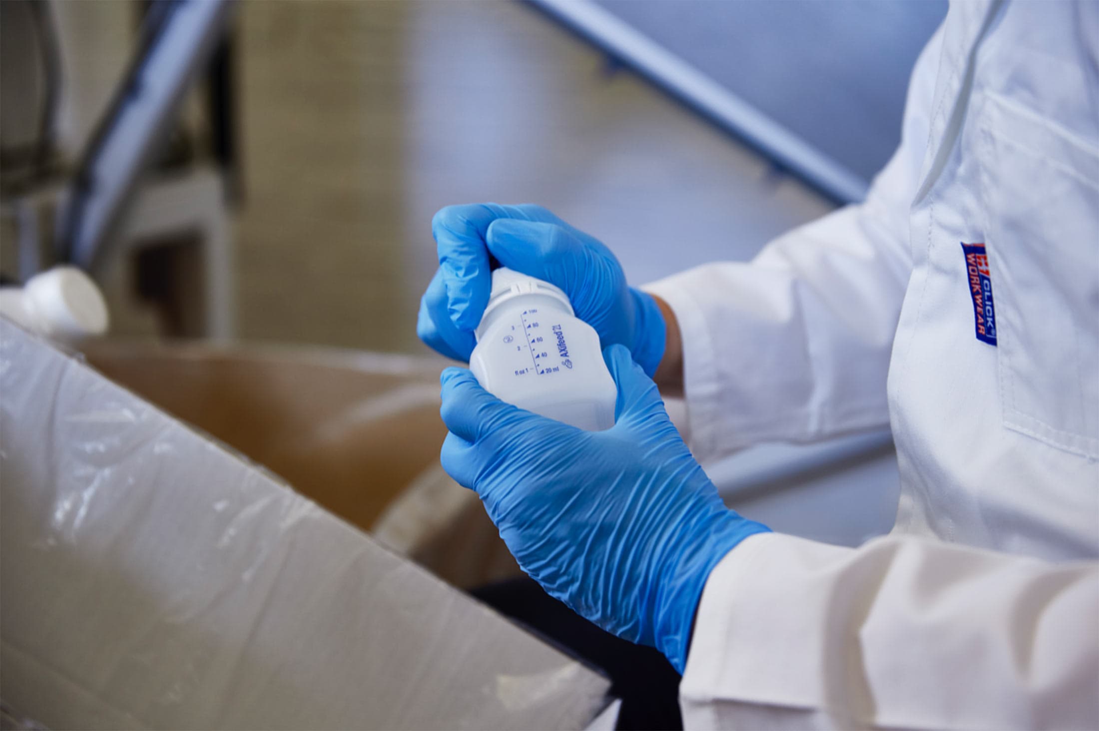 Gloved hands checking a graduated white plastic bottle