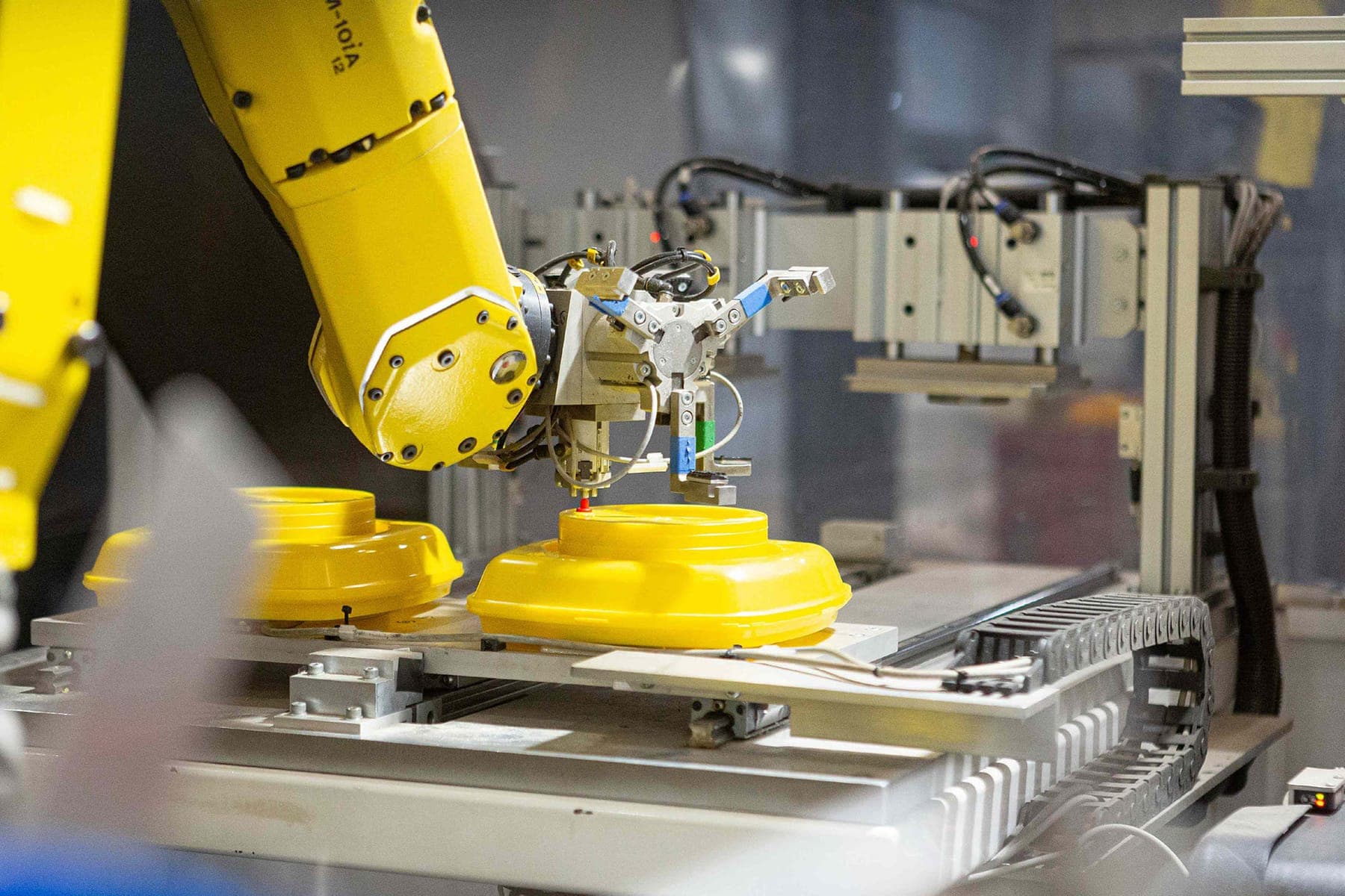 Robot arm handling yellow moulded lids on an automated line